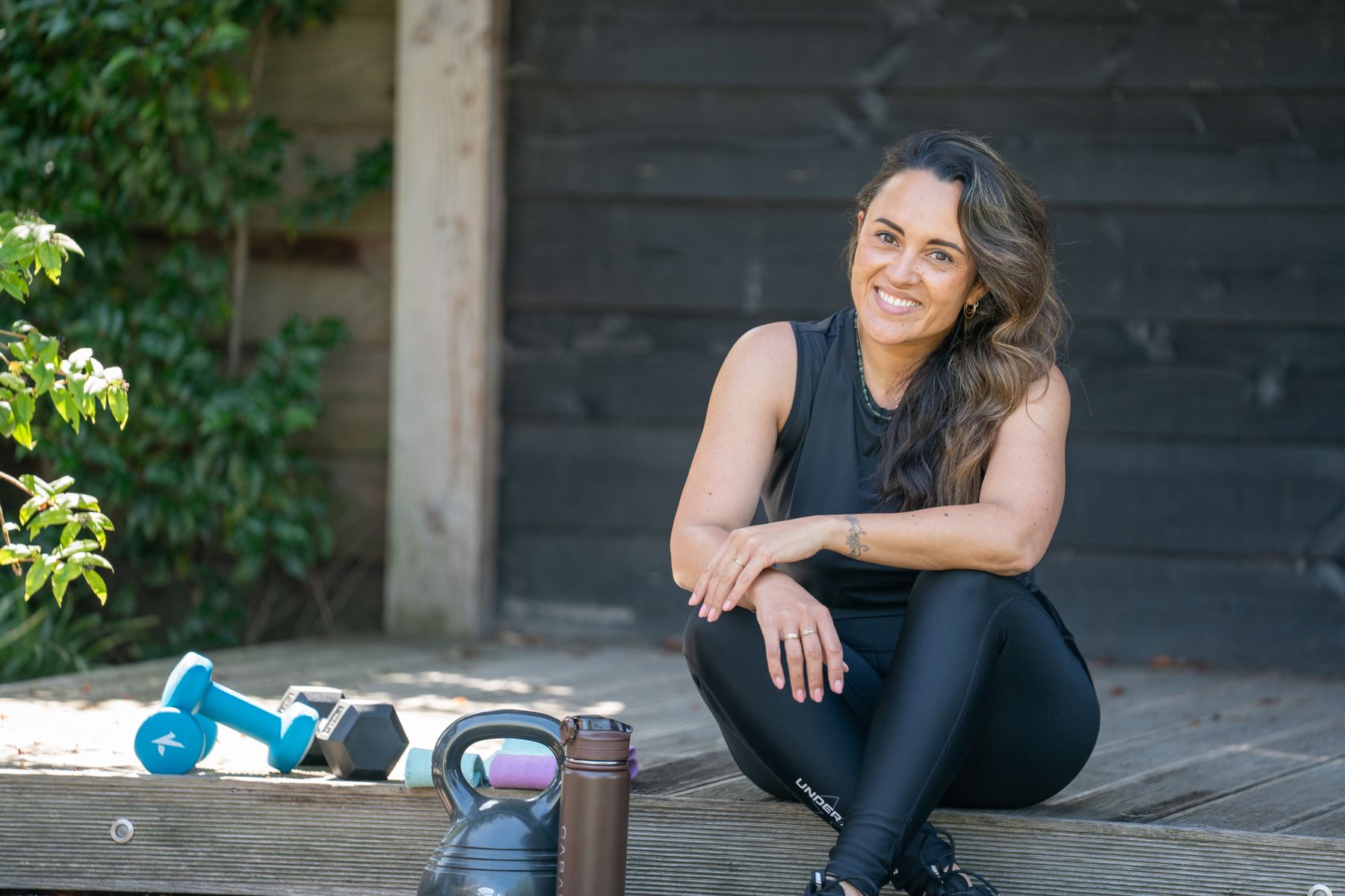 Romy zit gehurkt naast een kettlebell in de tuin