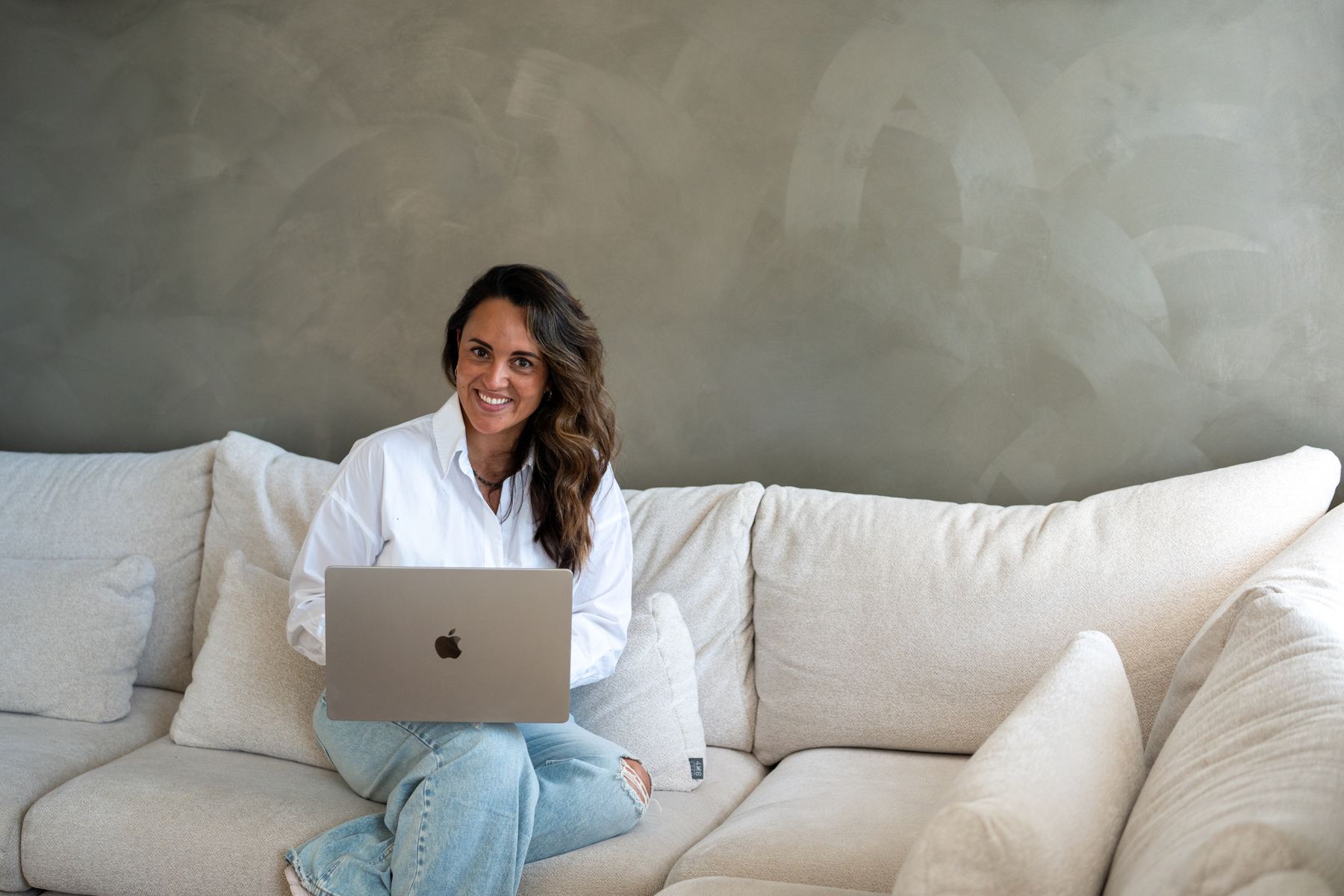 Romy Bitter zit met een laptop op een lichte bank