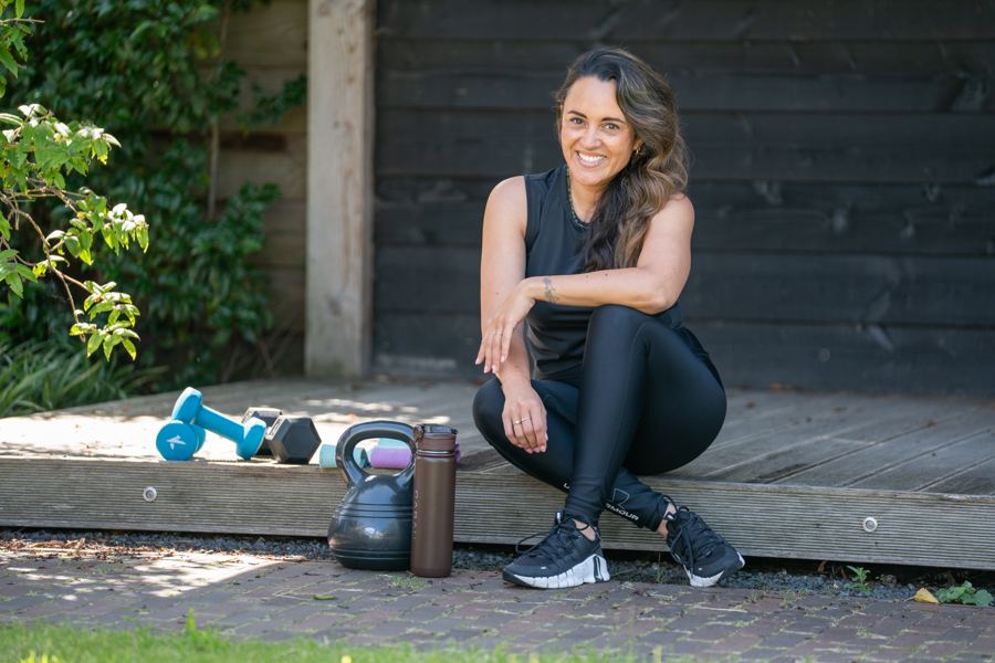 Romy in sportkleding naast kettlebells en dumbbells