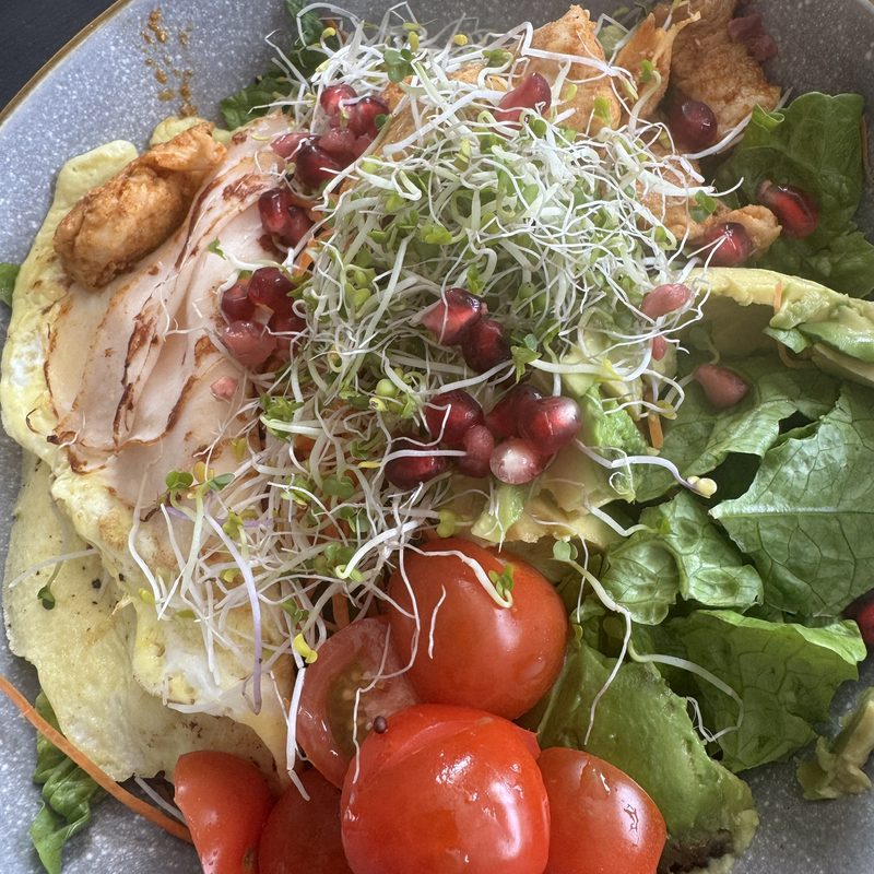 Bowl with chicken, salad, cherry tomatoes, pomegranate and sprouts